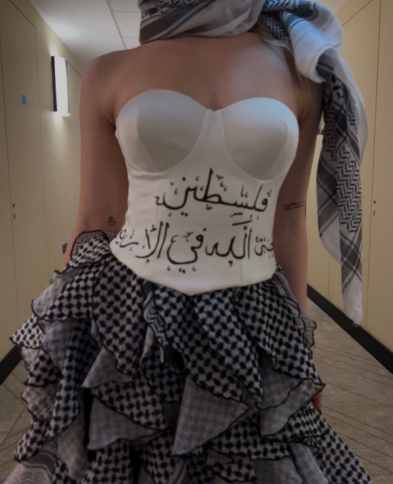 Atelier Qeblawi Calligraphy Gown — close-up of the bodice with hand-painted Arabic calligraphy reading 'Palestine, paradise of God on earth' in classical script.